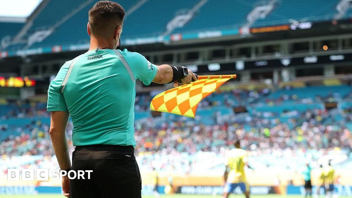 Assistant referee Gary Beswick signalling with his flag during a Club World Cup match featuring a superimposed graphic of FIFA's new offside technology.