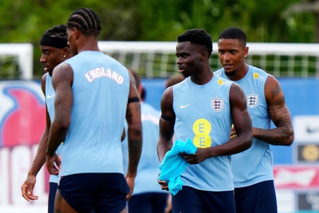 Bukayo Saka and Declan Rice arriving at England's Florida training camp, greeted by teammate Anthony Gordon before the 2026 World Cup.