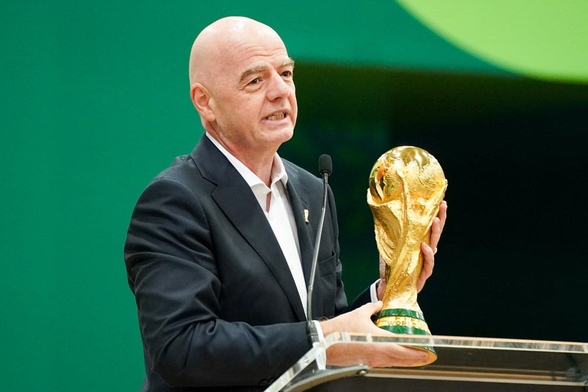 FIFA President Gianni Infantino smiling on stage while presenting a trophy next to a frowning Michel Platini, symbolizing their fractured relationship.