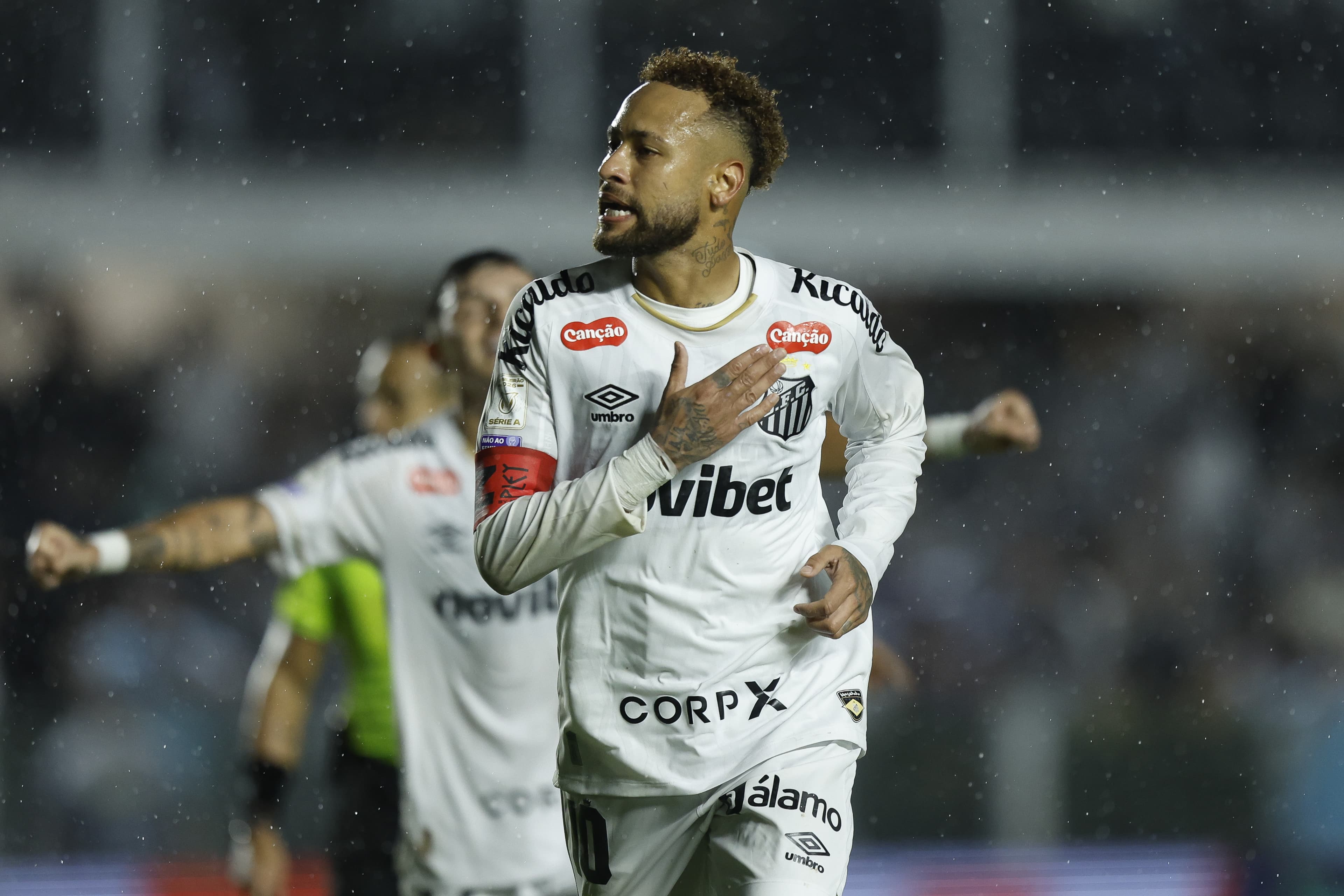 Neymar grimacing and clutching his right calf during training with Santos, with concerned teammates in the background.